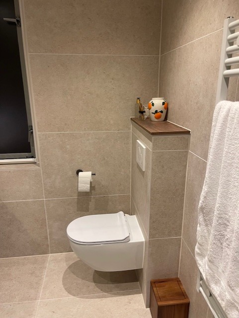 Gerenoveerd toilet met grote beige tegels